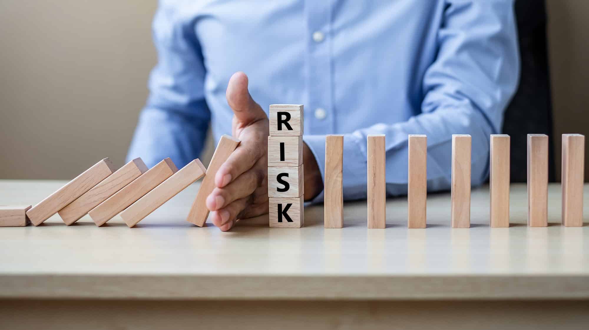 software-development-risk-mititigation-denoted-by-falling-block-dominos-with-hand-stopping-them-from-falling